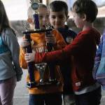 Emerson Elementary School students Ashton Balesteri, orange sweater, and Dayton Keys, red sweater, admire a trophy won by race car driver Zack Simpson on Vehicle Day on June 13. (Hasani Grayson | Grays Harbor News Group)