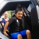 Emerson Elementary School Benjamin Silva slides through the back of Hoquiam Police Department car on Vehicle Day on June 13. (Hasani Grayson | Grays Harbor News Group)