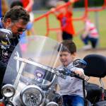 Emerson Elementary School Student Andre Collins sits on a motorcycle owned by Mike Cowan, right, on Vehicle Day on June 13. (Hasani Grayson | Grays Harbor News Group)