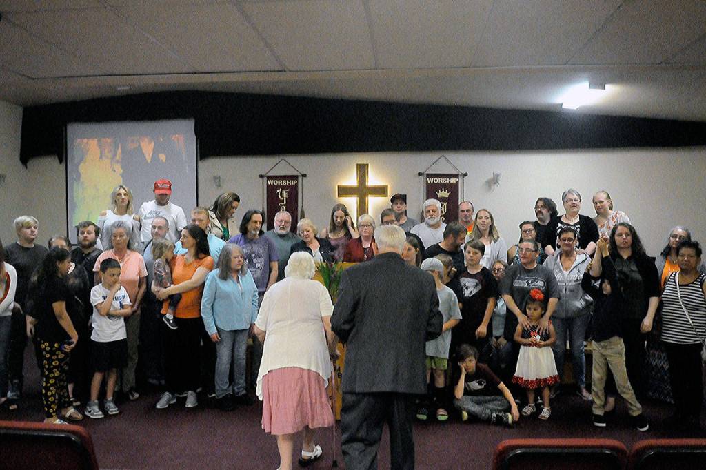 Delma Gilroy, left and John Gilroy, right, walk towards the front of the chapel to take a family photo with all their blood relatives in attendance at the couples 70-year anniversary Lake Quinault Valley Chapel on Saturday. (Hasani Grayson | Grays Harbor News Group)