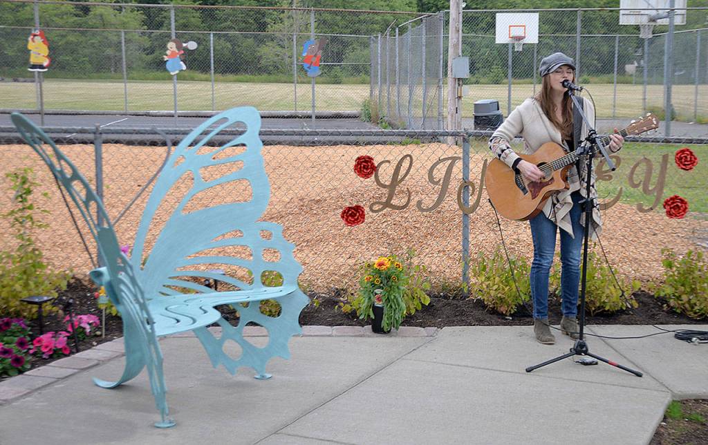 DAN HAMMOCK | GRAYS HARBOR NEWS GROUP                                Ericka Corban performs at the Lindsey Baum remembrance garden dedication at Beerbower Park in McCleary Wednesday. At left is the butterfly bench purchased by an anonymous donor.