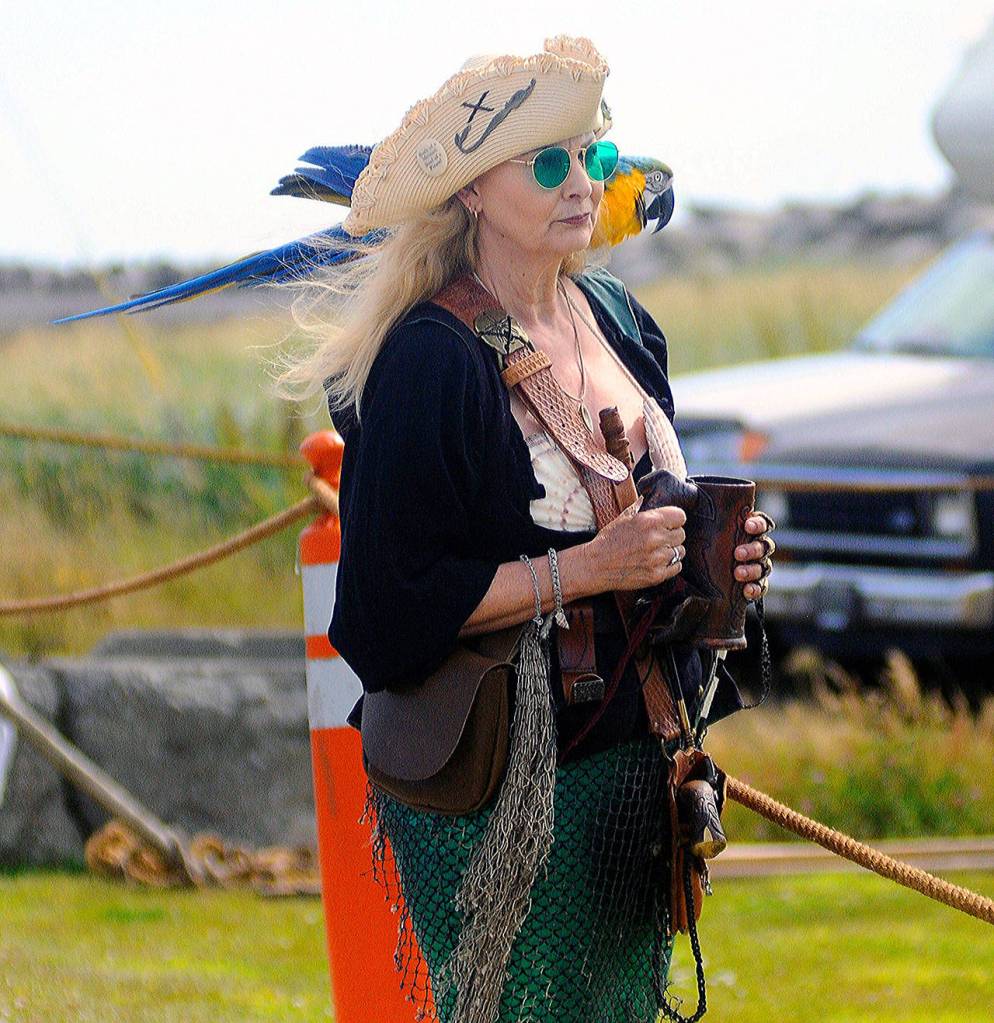 Janet Axton and her parrot Calipso take in a cannon demonstration during Pirate Daze at the Marina in Westport on Saturday. (Hasani Grayson | Grays Harbor News Group)