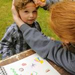 Volunteer Hannah Barre paints a rainbow on 3-year-old Skyler Burlingame during Family Reunification Day at Lake Aberdeen on June 22.                                Courtesy photo