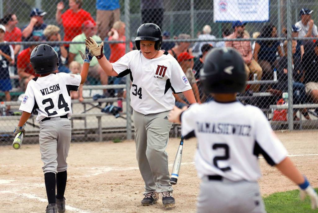 Montesanos Max Peterson, middle, is congratulated by teammates after scoring a run in the 8-10 year-old Little League State Tournament on Saturday. (Photo by Larry Bale)