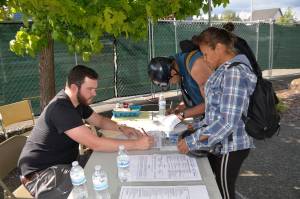 (Louis Krasuss | Grays Harbor News Group) Aberdeen Mayor Erik Larson, left, signs in Aaron and Jami Obi at the citys new overnight homeless facility in the City Hall parking lot Monday afternoon.