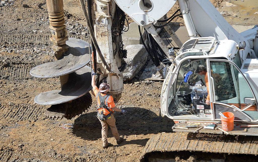 Photos by DAN HAMMOCK | GRAYS HARBOR NEWS GROUP                                Precision is key in the latest, more permanent effort to shore up a slide-prone section of Highway 101 at Cosi Hill. Here a worker holds a level to a crane used to drill holes to be filled with cobble. The shafts vary from 20-50 feet deep and must be drilled to less than 2 degrees of perpendicular to meet engineers standards.