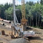 DAN HAMMOCK | GRAYS HARBOR NEWS GROUP                                The busy Cosi Hill stabilization site is making headway. At left, dump trucks enter and dump off loads of cobble and take away loads of soil removed by drilling. The white crane in the center drills the holes  575 when its all said and done  and the yellow crane behind it uses a vibrating weight to drive in the shafts that will hold the cobble temporarily.
