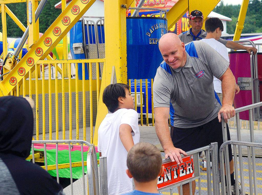 Carnival worker Albert Horton welcomes children onto the ferris wheel at the Grays Harbor County Fair on Friday. (Hasani Grayson | Grays Harbor News Group)