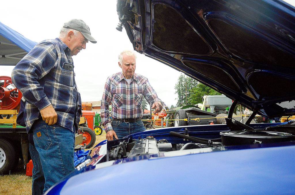 Junior Parris, left, and Tim Stangeland check out the engine of Parris El Camino at the Grays Harbor County Fair on Friday. (Hasani Grayson | Grays Harbor News Group)