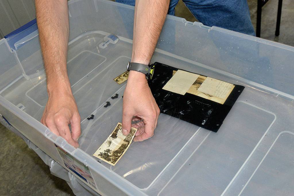 Photo by Louis Krauss | Grays Harbor News Group)                                Volunteer Mark Vessey cleans off historic photos recovered from the Aberdeen Museum of History archives in June 2018.