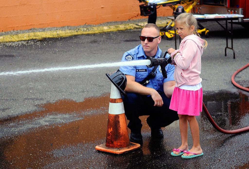 Emmalynn gets her chance to use a firehose from of fire truck from the Aberdeen Fire Department at Summerfest on Saturday. (Hasani Grayson | Grays Harbor News Group)