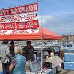 DAN HAMMOCK | GRAYS HARBOR NEWS GROUP                                It was a busy day Saturday at the Westport Marina. More than 60 vendors lined Westhaven Drive for the annual art festival, and charter boats were returning from salmon, bottom-fish and tuna trips. Here the charter boat <em>Hula Girl</em> returns to the dock as people line up at the Bay City Sausage food booth.