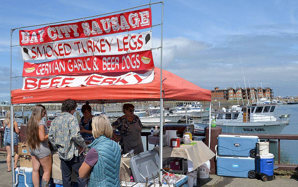 DAN HAMMOCK | GRAYS HARBOR NEWS GROUP                                It was a busy day Saturday at the Westport Marina. More than 60 vendors lined Westhaven Drive for the annual art festival, and charter boats were returning from salmon, bottom-fish and tuna trips. Here the charter boat <em>Hula Girl</em> returns to the dock as people line up at the Bay City Sausage food booth.