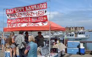 DAN HAMMOCK | GRAYS HARBOR NEWS GROUP                                It was a busy day Saturday at the Westport Marina. More than 60 vendors lined Westhaven Drive for the annual art festival, and charter boats were returning from salmon, bottom-fish and tuna trips. Here the charter boat <em>Hula Girl</em> returns to the dock as people line up at the Bay City Sausage food booth.