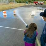 Kat Bryant | Grays Harbor News Group                                Hoquiam firefighter Matt Schmitz backs up a young future firefighter as she douses flames during the carnival at Immanuel Baptist Church on Saturday.