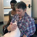 Courtesy photo                                Grays Harbor PAWS volunteer Amy Bates kneels next to Pacific Care resident Frannie Brown as she cuddles with Spot, one of the Aberdeen shelters adoptable cats. Bates visits the Hoquiam facility every Tuesday with a few PAWS residents in tow. The residents look forward to her coming, said Shannon Ashlock, activity director at Pacific Care.