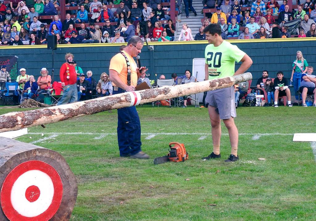 Emcee Don Bell chats with competitor Chester Isaacson after his chainsaw ripped off part of his loose gym shorts.
