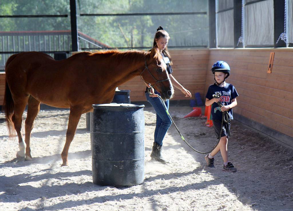 Michael Lang | Grays Harbor News Group                                Trent Meeks, 9, leads TeeJay around barrels with Horse Prayer volunteer Hailey Jones.
