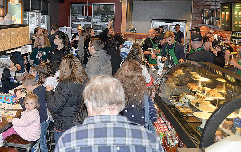 The Aberdeen Starbucks was packed Oct. 2 for the Aberdeen Police Department Coffee with a Cop event. At left is a table of kids coloring pictures while they are fingerprinted. At right, officers and Aberdeen Mayor Erik Larson participate in a latte-making contest.