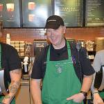 Aberdeen Police Officer Gary Sexton, center, is flanked by Starbucks employees Zach Grebenc and Holly Bergeson as he mans the register at the Wishkah Street Starbucks during the Coffee with a Cop event.