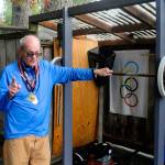 Paul Roberts stands next to his homemade squat rack in his backyard while wearing the medals he earned at the World Senior Games earlier this year. (Hasani Grayson | Grays Harbor News Group)
