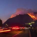 Los Angeles Times/TNS                                 Traffic continues as flames roar up a steep hillside near the Getty Center in Los Angeles. The blaze forced evacuations and has burned more than 600 acres.