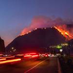 Traffic continues as flames roar up a steep hillside near the Getty Center in Los Angeles. The blaze forced evacuations and has burned more than 600 acres. (Los Angeles Times/TNS)