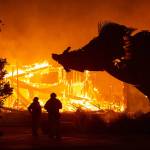 A huge sculpture of a boar looms over two firefighters as the Soda Rock Winery is consumed by the Kincade Fire early Sunday morning, Oct. 27, 2019, near the Sonoma County town of Healdsburg. (Jason Pierce/Sacramento Bee/TNS)