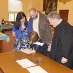Gianna signs her adoption certificate while her new parents and Judge Stephen Brown watch Friday during the National Adoption Day ceremony in Judge Stephen Browns courtroom at Grays Harbor County Superior Court in Montesano. (Michael Lang | Grays Harbor News Group)