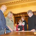 The Robles family  Sean (from left), Terri, Eric and Julianna  watches as Eric finishes signing an adoption certificate Friday during the National Adoption Day ceremony in Judge Stephen Browns courtroom at Grays Harbor County Superior Court in Montesano. (Michael Lang | Grays Harbor News Group)