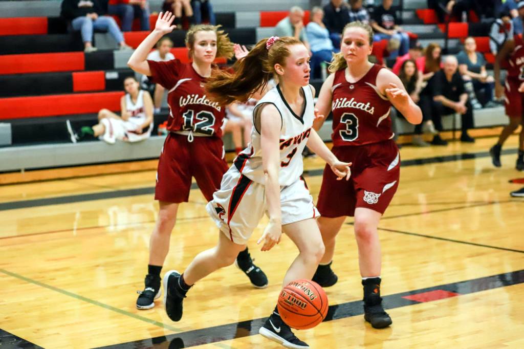 Raymonds Izzy Silvernail, middle, drives the baseline against Ocostas Layne Martin (3) and Mikayla Ness (12) during Saturdays game in Raymond. (Photo by Larry Bale)