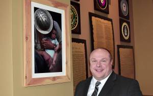 DAN HAMMOCK | GRAYS HARBOR NEWS GROUP                                Hoquiam Mayor Ben Winkelman stands by a photo of his dad, Mario Winkelman, and his youngest brother Bryce taken at Camp Grisdale the year it closed, which hangs in the Jitter House in Hoquiam. The Winkelman family had its roots in the logging camp.