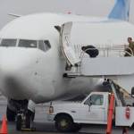 An unidentified detainee, right, in handcuffs locked to a belt chain, manages to wave to activists as he boards a U.S. Immigration and Customs Enforcement flight in Yakima. (Richard Read/Los Angeles Times/TNS)