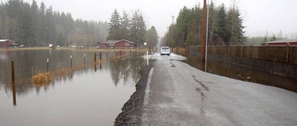 A vehicle drives through water flowing over Newman Creek Road into a field near Satsop on Tuesday. The National Weather Service in Seattle issued a flood warning for the Satsop River. (Michael Lang | Grays Harbor News Group)