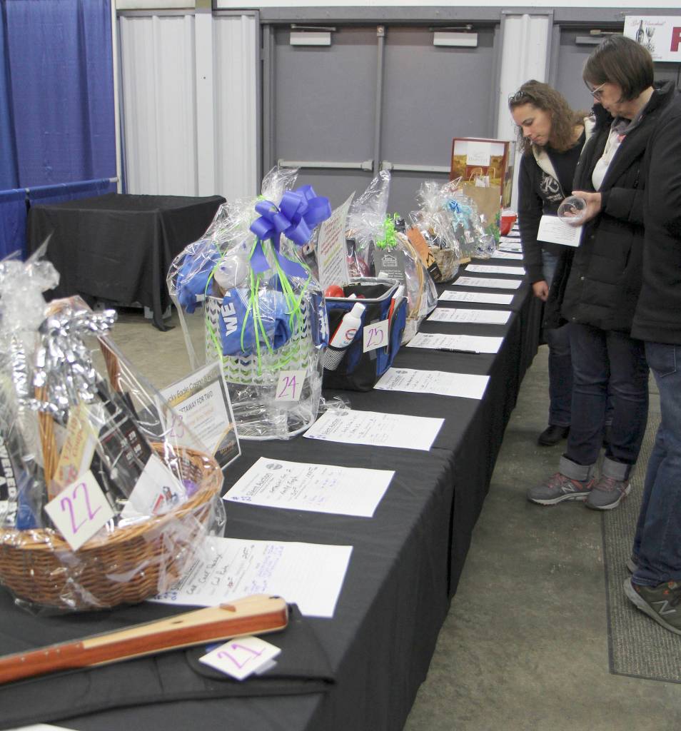 Cher Cole of Grayland (from left) and Judy Meeds of Castle Rock check out the auction table Saturday at the Winter Wine Festival in Elma. (Michael Lang | Grays Harbor News Group)