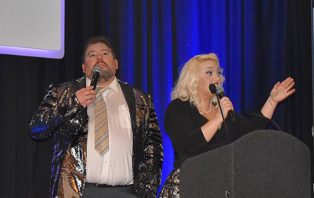 DAN HAMMOCK | GRAYS HARBOR NEWS GROUP                                Phil Luce and Logan Livingston served as auctioneer for the 12 live auction items offered at the United Way of Grays Harbor Black and White Gala fundraiser in Ocean Shores Saturday. Here they take bids for the Toes in the Water package, seven nights in Mexico.