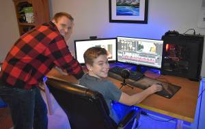 DAN HAMMOCK | GRAYS HARBOR NEWS GROUP                                 Aberdeen Police Officer Loren Neil and his 14-year-old son, Aiden, at the computer where the two spent countless hours producing a video.