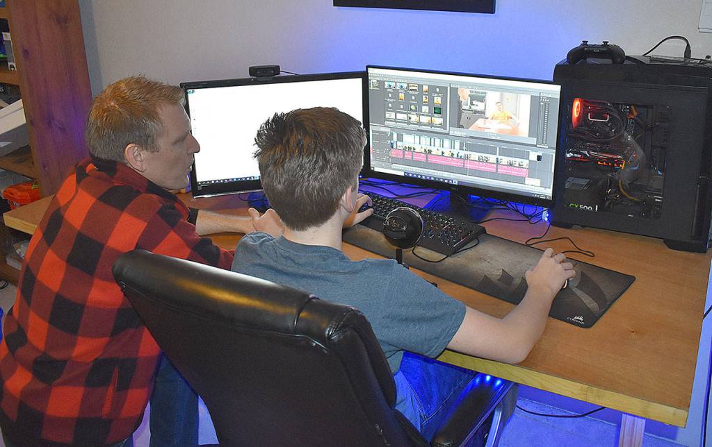 DAN HAMMOCK | GRAYS HARBOR NEWS GROUP                                 Aberdeen Police Officer Loren Neil and his 14-year-old son, Aiden, at the computer where the two spent countless hours producing a video.