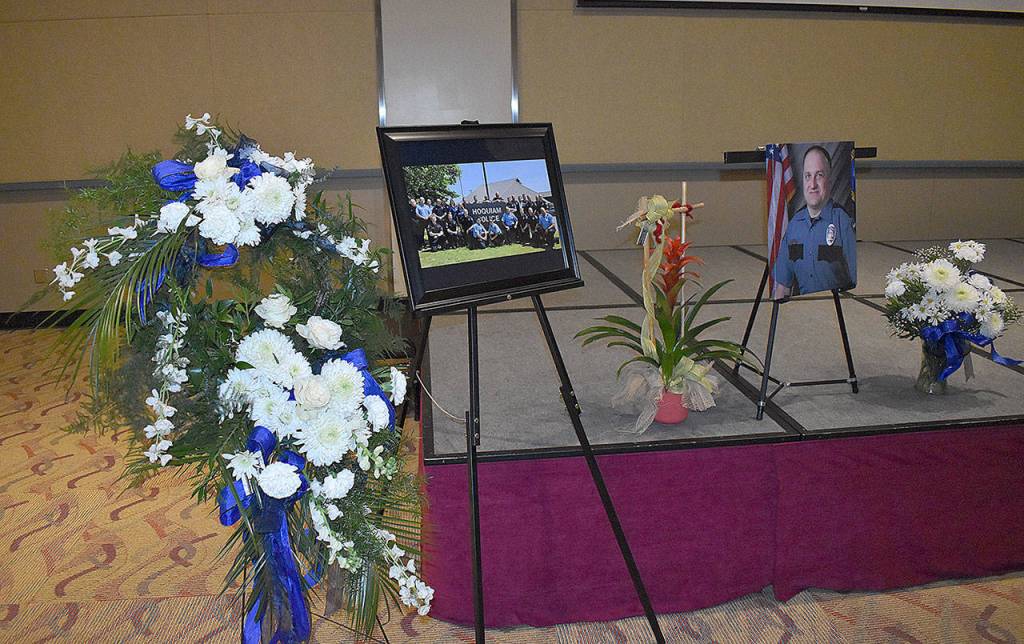 DAN HAMMOCK | GRAYS HARBOR NEWS GROUP                                 Flowers and photos lined the stage at Hoquiam Police Officer Phil Highs memorial service in Ocean Shores Saturday. Hoquiam Police Chaplain Sean Hollen delivered the invocation.