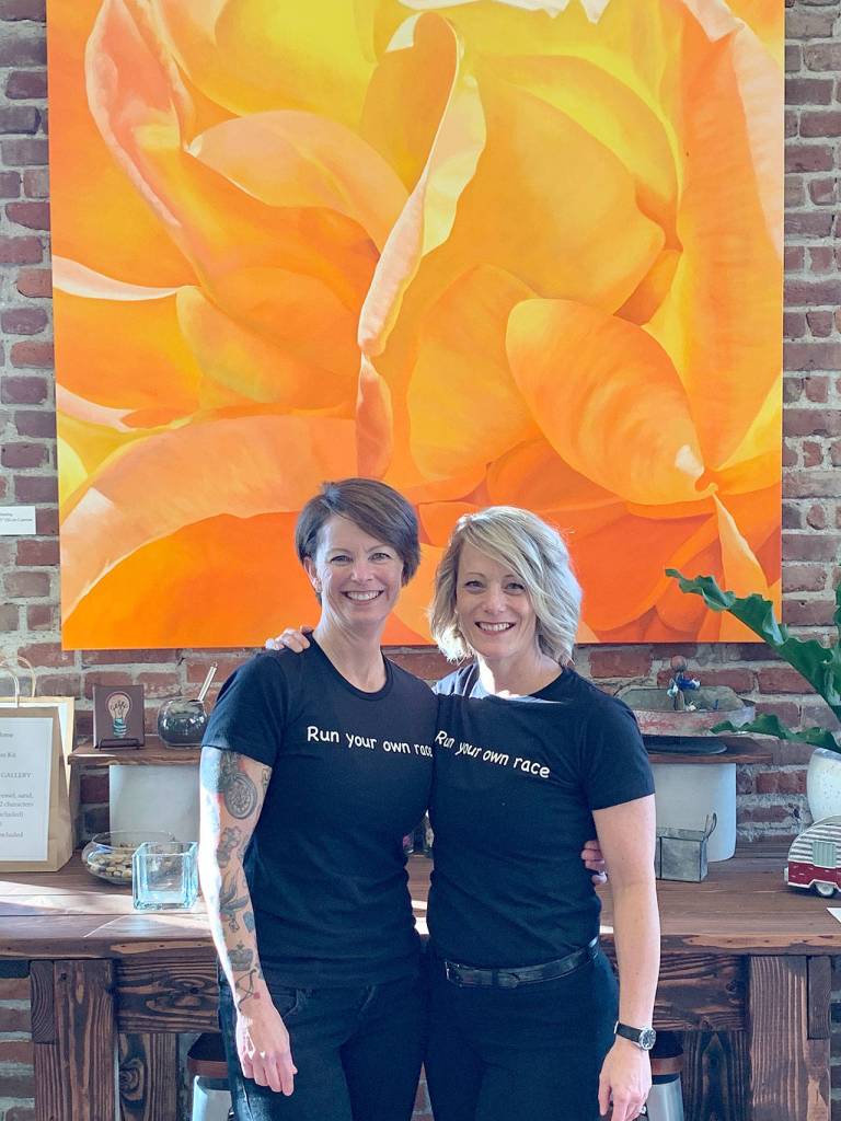 Trina (left) and Tammy Moore, co-owners of the Moore Gallery, in front of one of Trinas larger paintings. (Photo courtesy Trina Moore)