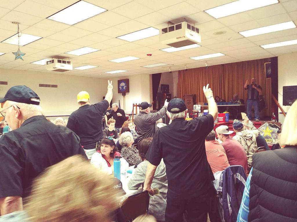 Spotters hold up fingers, letting the auctioneer know how many dollars each bidder wants to risk for a particular item during the annual Chinese auction held by the Hoquiam Push Rods on Sunday.