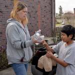 Feed the Hungry program director Cher Keller passes out lunches to Benito Rodriguez behind the St. Marys Catholic Church on Wednesday. (Thorin Sprandel | Grays Harbor News Group)