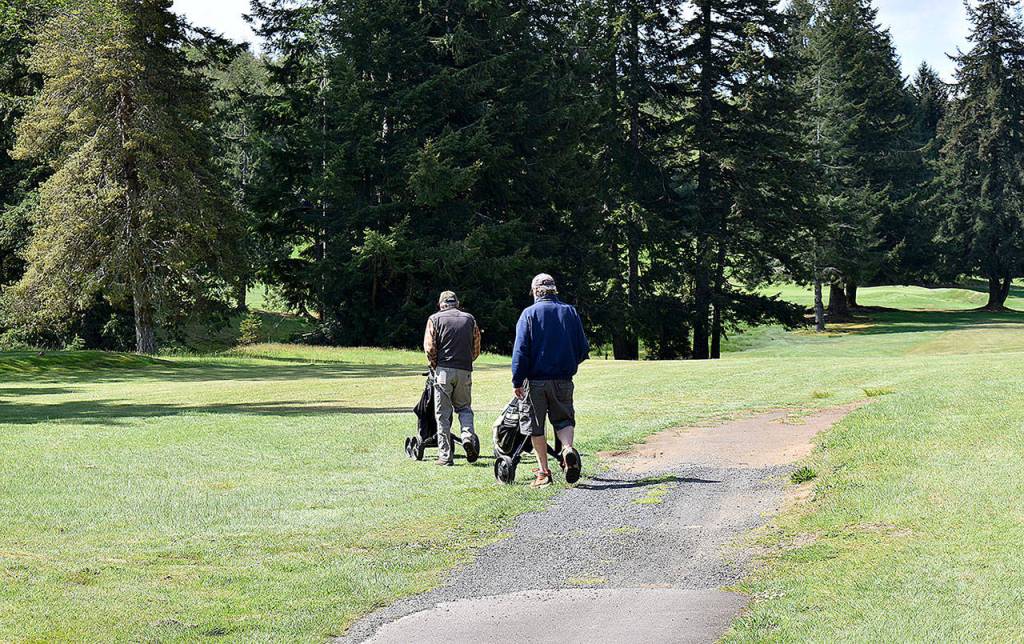 A twosome heads out to play a round of golf at Highland Golf Course in Cosmopolis Tuesday morning.
