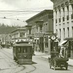 I Street (now Simpson) looking north from 8th Street. Heikels Drug is visible at 721 I Street in the First National Bank building at right, its sign nestled between the street clock and the Grayport Hotel sign. All street car patrons were required to wear masks at the height of the pandemic.