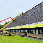 COURTESY PHOTO                                 Replacement of the old cedar shakes at Hoquiam High School is underway. Here you can see the new composite shakes going up, which match the look of the Mansard-style roof and will hold up to Hoquiam weather.