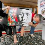 Lummi tribal members Teresa Taylor and Freddie Lane secure a Washington Native Vote Day sign outside the tribe's Administration Building on Oct. 7, north of Bellingham. The image on the sign is one by Edward Curtis titled "Lummi Woman" from 1899, modified to encourage Lummi tribal members to vote. (Alan Berner/Seattle Times)