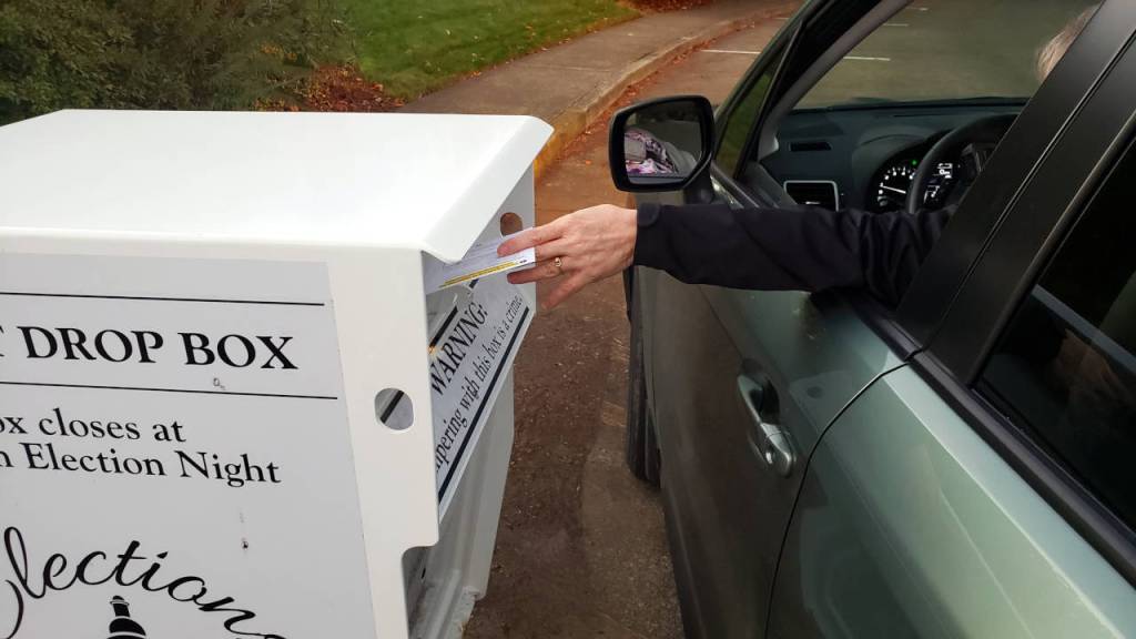 A voter drops off their ballot at a ballot box in Montesano on Monday. (Ryan Sparks | The Daily World)