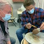 Gary Ganz, right, shows fellow guild member Ken Slaughter the ancient art of Terra Sigillata clay painting. (Kat Bryant | The Daily World)