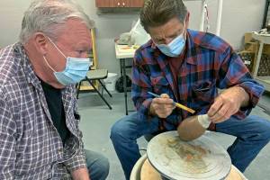 Gary Ganz, right, shows fellow guild member Ken Slaughter the ancient art of Terra Sigillata clay painting. (Kat Bryant | The Daily World)