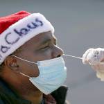 Tim Tai/The Philadelphia Inquirer/TNS 
Anthony Harvin wears a Santa hat as he receives a coronavirus test from Dante Terracciano of Philly Fighting COVID at Vine Memorial Baptist Church in West Philadelphia on Saturday. Staff from Philly Fighting COVID and the Childrens Hospital of Philadelphia offered free testing organized by the traveling Community-Accessible Testing & Education (CATE) program, which offers testing at different sites across Pennsylvania.